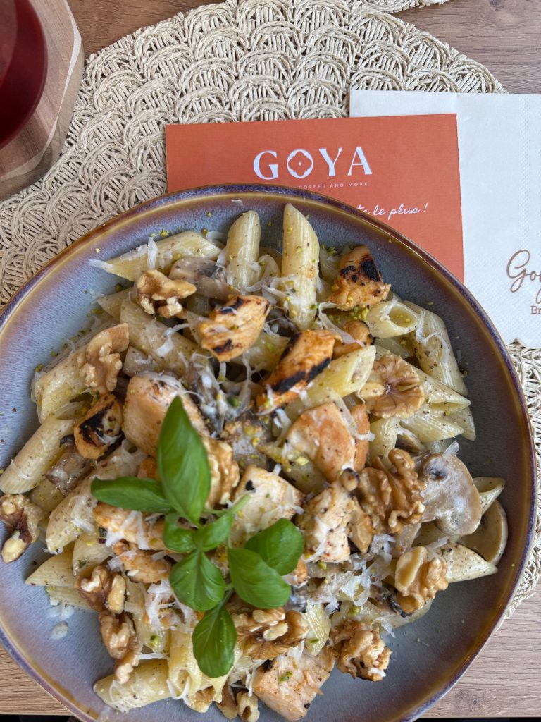 Délicieux plat de penne au poulet grillé, champignons, noix et parmesan, servi au café Goya